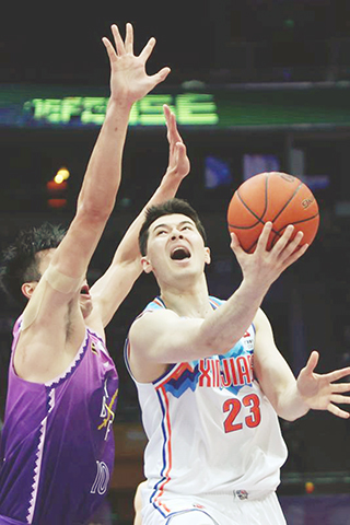 ◎ 十二月二十四日,新疆伊力特隊球員阿不都沙拉木(右)在比賽中上籃。CBA常規賽第二十二輪比賽中,北京控股隊主場九十三比一百不敵新疆伊力特隊。(新華社記者 雒圓 攝)