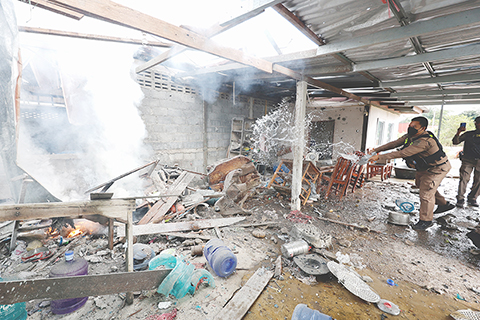 ◎ 十二月十一日,柬埔寨與泰國邊境衝突進入第五天。泰國和柬埔寨邊境地區七日爆發激烈衝突,多地響起密集炮火。雙方均指責對方「先開火」。圖為十一日,在泰國素林府,警察向被炮火損毀的房屋灑水滅火。(新華社發)