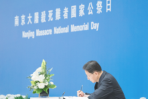 ◎ 十二月十三日是南京大屠殺死難者國家公祭日。中央人民政府駐香港特別行政區聯絡辦公室主任周霽簽署紀念册。(中新社記者侯宇 攝)