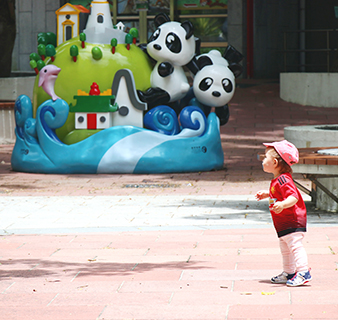可愛的小童在公園裏看到熊貓雕塑的好奇心。