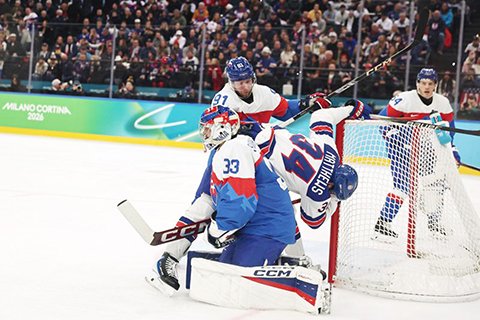 ◎ 二月二十日,美國隊球員馬修斯(中)與斯洛伐克隊球員蘇克爾(上)在比賽中拼搶。冬奧會冰球項目男子半決賽在意大利米蘭舉行,美國隊六比二戰勝斯洛伐克隊,晉級決賽。(新華社記者 王楷焱 攝)