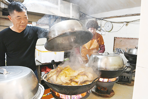 3月27日,閩南鹽雞傳統製作技藝代表性傳承人蔡建民掀開鍋蓋,金黃鹹香的鹽雞伴著熱氣出鍋。(中新社記者 張金川 攝)